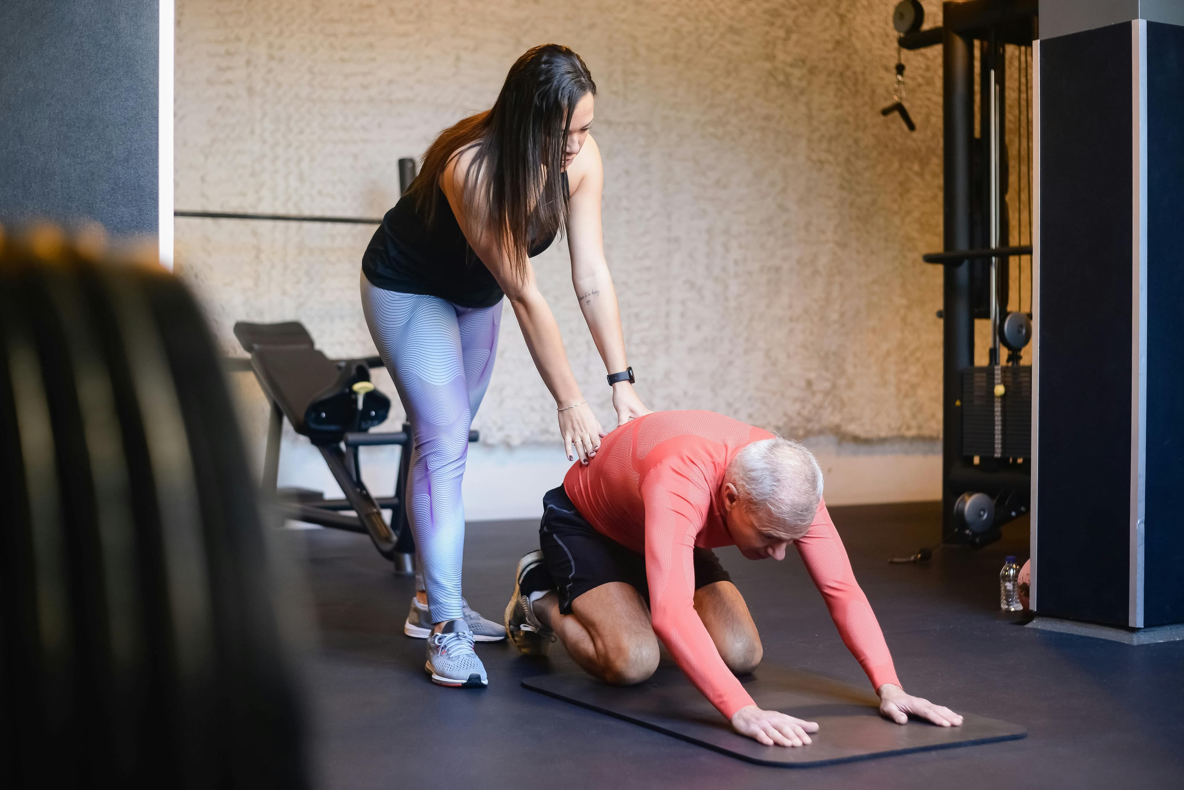 An exercise professional supporting an older adult during a floor exercise